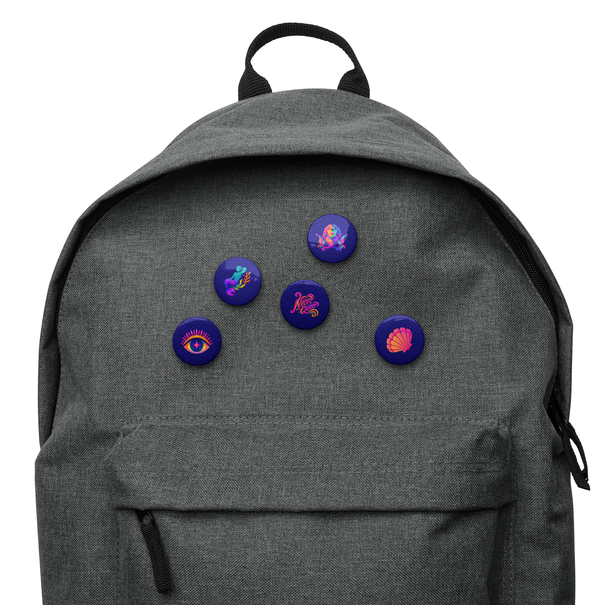 A dark gray backpack with five colorful circular pins attached to the front pocket. The pins feature various psychedelic designs, including a purple eye, a pink shell, and other abstract patterns on a dark blue background.